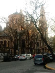 a large building with cars parked on the side of a street at Calido en Parque Lezama in Buenos Aires