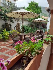 un patio con mesa, sombrilla y flores en Casona Santo Domingo, en Villa de Leyva