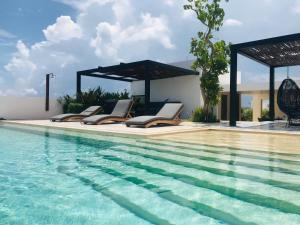 a pool with lounge chairs next to a house at Riva Playasur 405 in Playa del Carmen