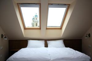 um quarto com duas janelas e uma cama com lençóis brancos em Publo Étterem és Panzió em Csákvár
