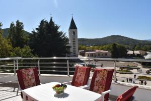 d'un balcon avec une table, des chaises et une tour d'horloge. dans l'établissement Gloria Apartments 1, à Međugorje