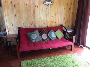 un sofá rojo con almohadas en una habitación en Cabañas Trancura con Internet Satelital, en Pucón