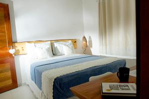 a bedroom with a bed with a blue blanket and a table at Villa Água de Coco in Jericoacoara