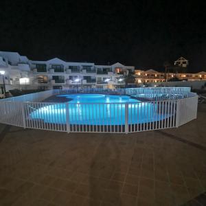 una piscina por la noche con edificios en el fondo en Apartamentos Tahiche, en Costa Teguise