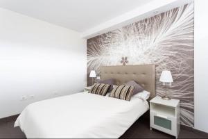 ロス・クリスティアーノスにあるVacation Home 1 Bed Los Cristianosの白いベッドと壁画が備わるベッドルーム1室が備わります。