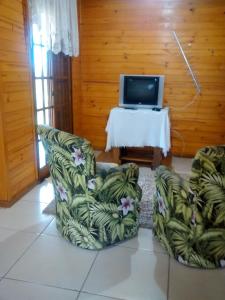 Itaara的住宿－Pousada Taiani，客厅配有两把椅子和电视
