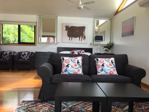 una sala de estar con sofá y una vaca en la pared en Black Cockatoo Cottages, en Yanakie