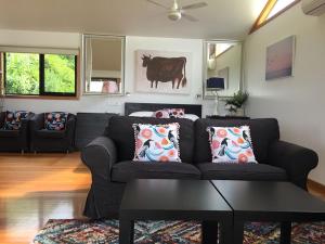 ein Wohnzimmer mit einem Sofa und einer Kuh an der Wand in der Unterkunft Black Cockatoo Cottages in Yanakie