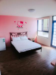 馬公市的住宿－愛琴海民宿，一间卧室配有一张粉红色墙壁的床
