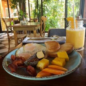 un plato de comida con carne y verduras y un vaso de zumo de naranja en Hotel Posada Las Orquídeas, en West End