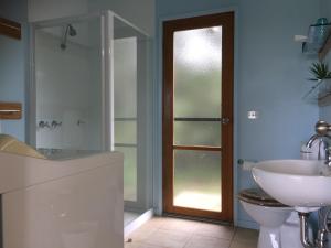 a bathroom with a sink and a toilet and a shower at Black Cockatoo Cottages in Yanakie