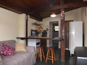 a living room with a couch and a table and stools at Chalé Barra Velha in Ilhabela