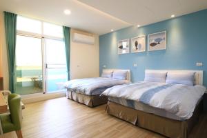 2 camas en una habitación con paredes azules y ventana en The Wind BnB Ⅱ, en Budai