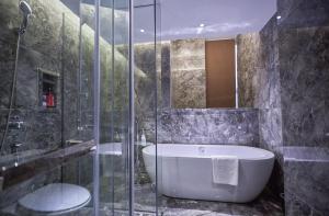 a bathroom with a tub and a glass shower at Paco Hotel Guangzhou Baiyun Airport Liantang Metro in Huadu