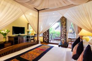 Cette chambre comprend un lit avec des rideaux et une télévision. dans l'établissement Amata Lanna Chiang Mai, One Member of the Secret Retreats, à Chiang Mai