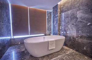 a white bath tub in a bathroom with black tiles at Paco Hotel Guangzhou Baiyun Airport Liantang Metro in Huadu
