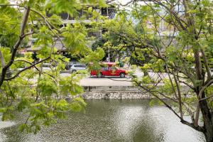 ein rotes Auto, das neben einem Wasserkörper parkt in der Unterkunft MiLa Thapae@Chiang Mai Old City in Chiang Mai