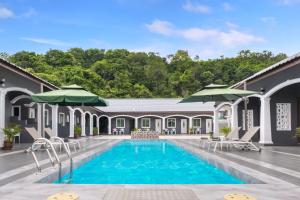 a villa with a swimming pool and umbrellas at Cenang Rooms With Pool by Virgo Star Resort in Pantai Cenang