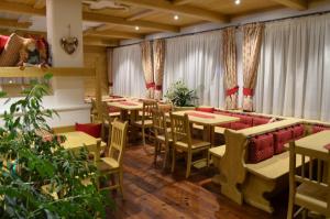 un ristorante con tavoli, sedie e tende di Hotel Ladina a Campitello di Fassa
