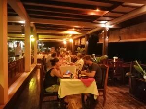 un grupo de personas sentadas en una mesa en un restaurante en Pon Arena Hotel, en Muang Không
