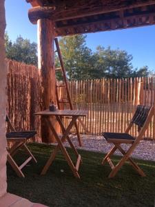 a picnic table and two chairs in a yard at Chambre d hôte piscine spa in Alba La Romaine