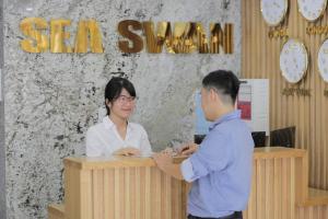 Ein Mann und eine Frau stehen an einem Schreibtisch in der Unterkunft Sea Swan Apartment and Hotel in Đà Nẵng