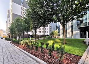 a park with trees and grass and buildings at Come&Stay apartments Wola in Warsaw