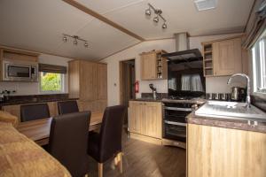 - une cuisine avec des placards en bois, un évier et une table dans l'établissement Robin's Retreat, à South Cerney