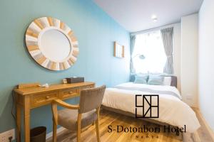 een slaapkamer met een bed en een bureau met een spiegel bij S-Dotonbori Hotel Namba - Self Check-In Only in Osaka