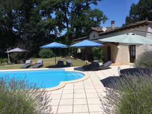 une piscine avec des parasols et des chaises ainsi qu'une maison dans l'établissement Domaine de Merugat Chambre d'Hôtes, à Valeilles