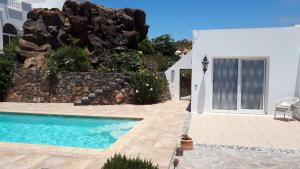 una piscina frente a una casa blanca en Villa Essence - a unique detached villa with heated private pool, hottub, gardens, patios and stunning views!, en Tías