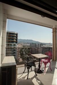 einen Balkon mit einem Tisch und Stühlen sowie einem großen Fenster in der Unterkunft Lion Park Suites & Residence Hotel in Aydın