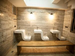 a public bathroom with three sinks and a wooden bench at Lion Park Suites & Residence Hotel in Aydın