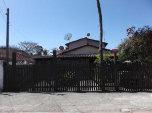 una cerca negra con una casa en el fondo en Chalé Barra Velha, en Ilhabela