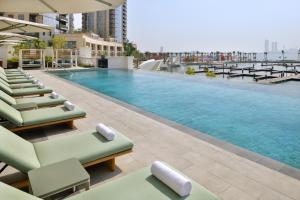 a pool on the roof of a building with lounge chairs at Vida Creek Harbour in Dubai