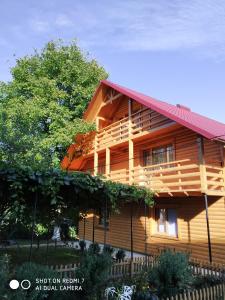 une grande maison en bois avec un toit rouge dans l'établissement Садиба Чорногора, à Yaremtche