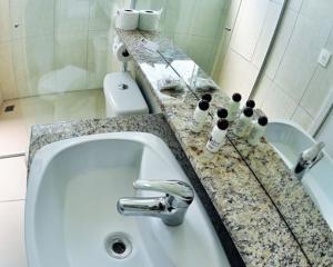 uma casa de banho com um lavatório e uma bancada em granito em Petry Plaza Hotel em Canoinhas