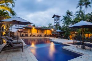 einem Pool mit Stühlen und Sonnenschirmen vor einem Gebäude in der Unterkunft Taman Harum Cottages in Ubud