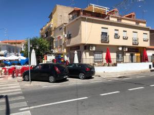 dos coches estacionados frente a un edificio con mesas y sombrillas en Apartamento Ruidera Plaza en Ruidera