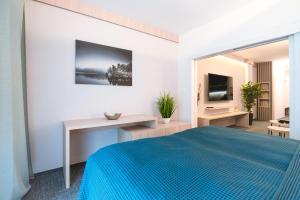 a bedroom with a blue bed and a television at Apartman Pod Hrebienkom - C218 in Starý Smokovec