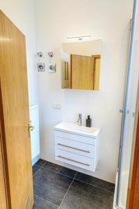 a bathroom with a white sink and a mirror at Charming City Apartment with parking spot in Würzburg