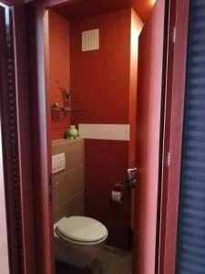 a bathroom with a toilet and a red wall at Room in maisonette with garden, parking place in Vienna