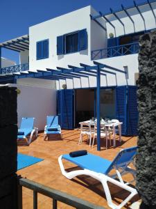 eine Terrasse mit Stühlen, einem Tisch und einem blauen Sonnenschirm in der Unterkunft Villa la 29 in Playa Blanca