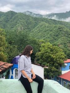 una mujer sentada en la cima de un edificio con una montaña en Copper Canyon Riverside Lodge, en Batopilas