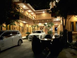 twee auto's geparkeerd voor een gebouw 's nachts bij A Little Bit of BAGAN HOTEL in Bagan