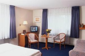 Kocks Hotel Garni في هامبورغ: غرفة فندقية بسرير وطاولة وكراسي