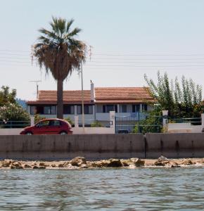 een rode auto geparkeerd voor een huis naast het water bij Eftichia Apartment in Roda