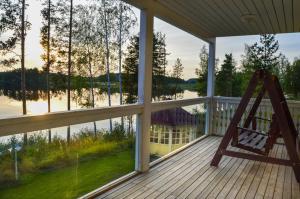 a porch with a rocking chair and a view of the water at Villa Rantakallio with jacuzzi in Melkoniemi