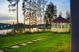 a small gazebo in the grass next to a lake at Villa Rantakallio with jacuzzi in Melkoniemi