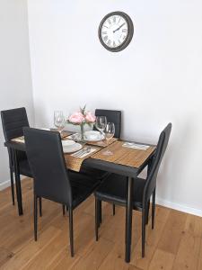 mesa de comedor con sillas y reloj en la pared en 168 - ExcellentStays - 2 Bedroom Flat en Stanwell